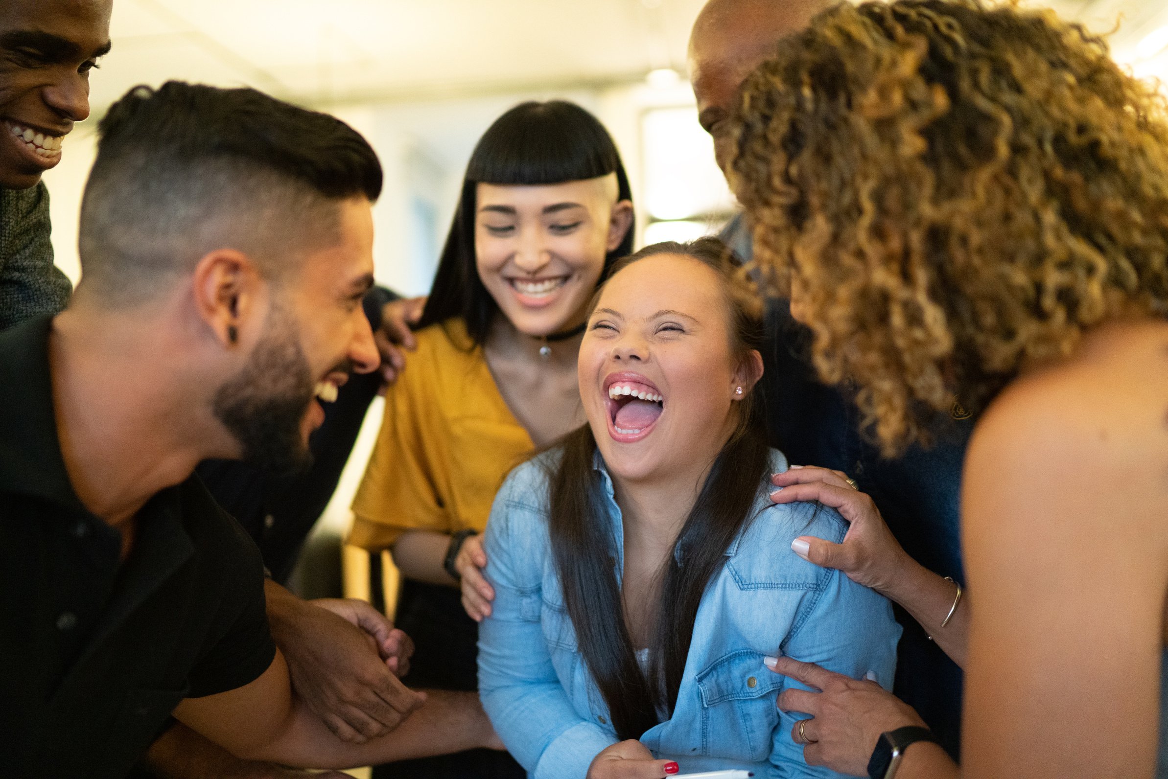 Coworkers embracing a  businessperson with down syndrome at workplace